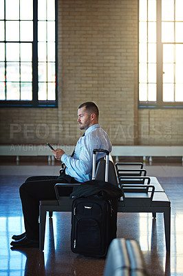 Buy stock photo Shot of a confident businessman using his smartphone while waiting in an airport terminal