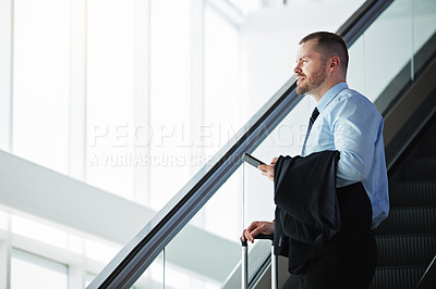 Buy stock photo Shot of a businessman traveling down an escalator in an airport