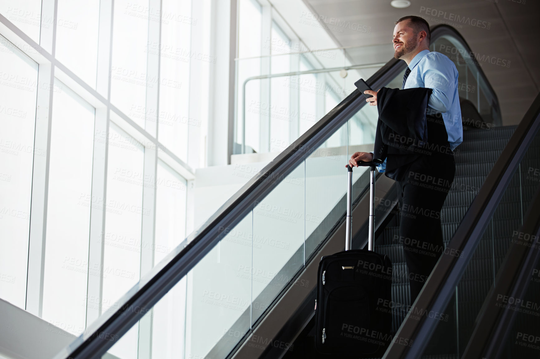 Buy stock photo Shot of a businessman traveling down an escalator in an airport