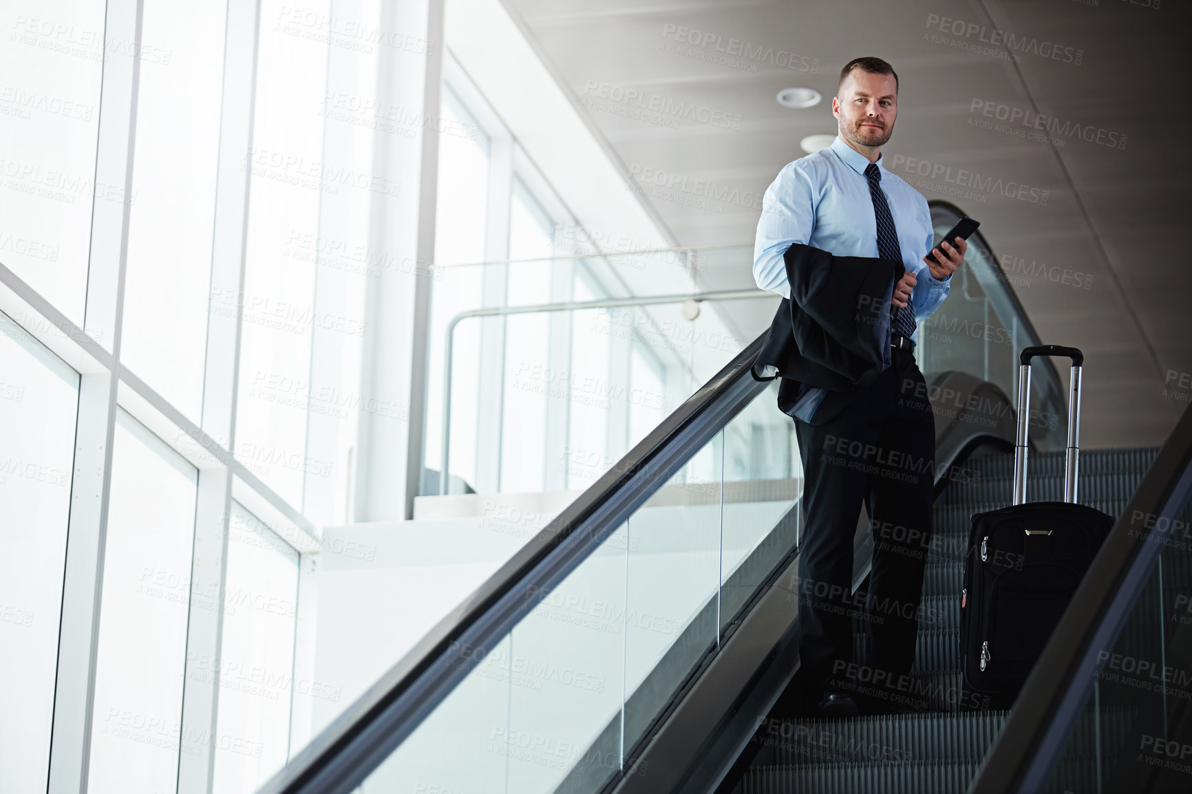 Buy stock photo Shot of a businessman traveling down an escalator in an airport