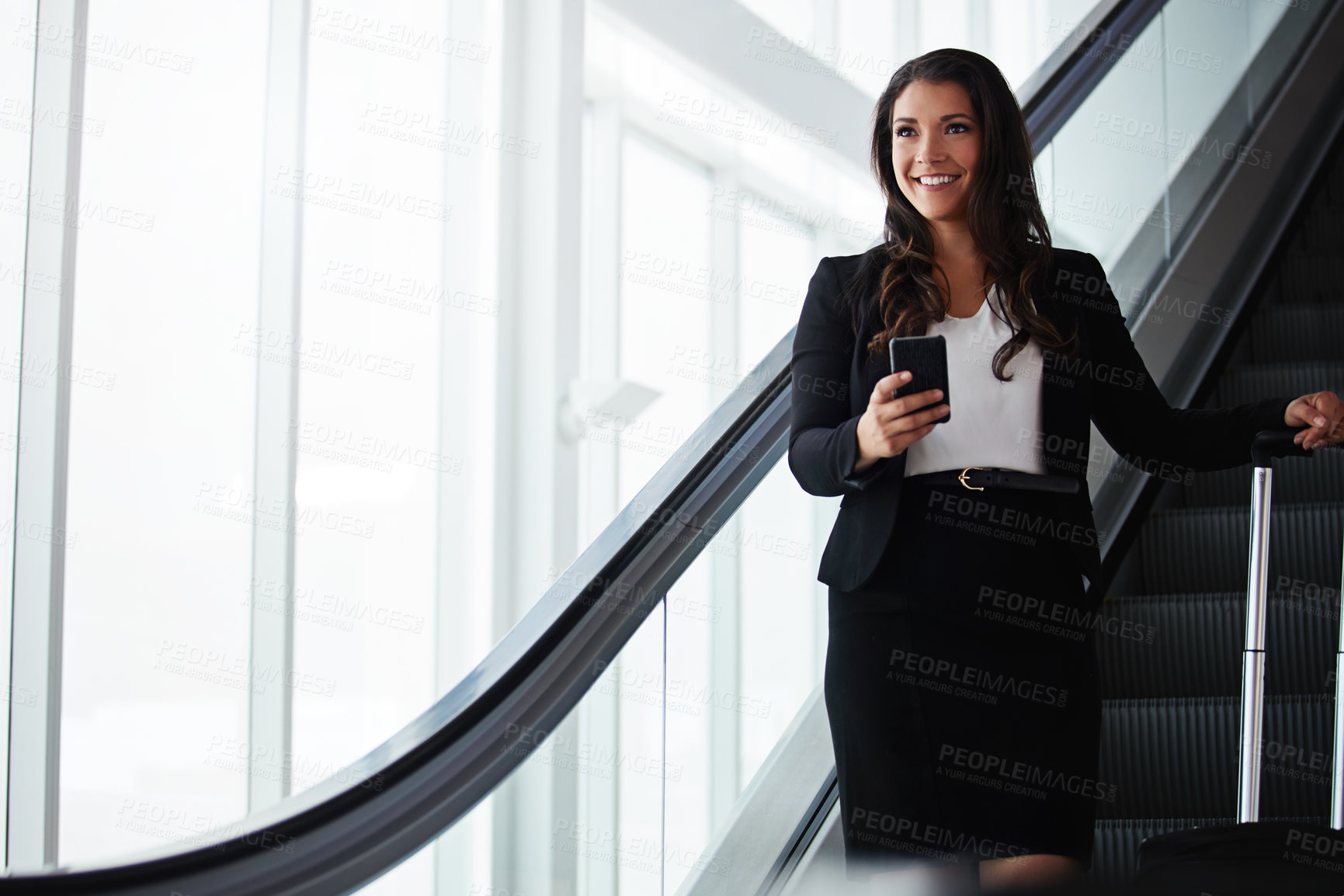 Buy stock photo Shot of a businesswoman traveling down an escalator in an airport