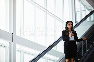 Buy stock photo Shot of a businesswoman traveling down an escalator in an airport