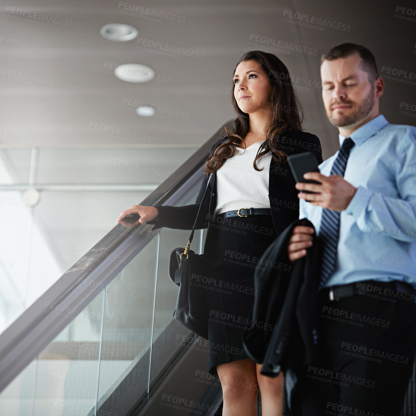 Buy stock photo Shot of a businessman using a mobile phone while traveling down an escalator in an airport