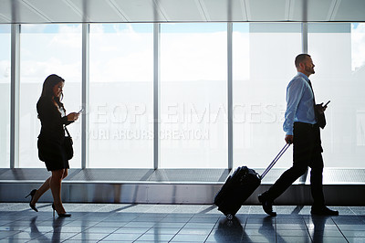 Buy stock photo Shot of businesspeople walking down a corridor in an airport while on a business trip