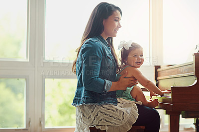 Buy stock photo Cropped shot of a mother playing the piano with her adorable little daughter at home