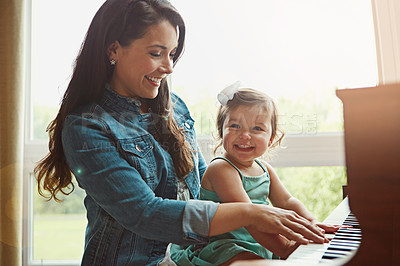 Buy stock photo Cropped shot of a mother playing the piano with her adorable little daughter at home