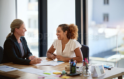 Buy stock photo Shot of two smiling businesswoman sitting in an office talking together