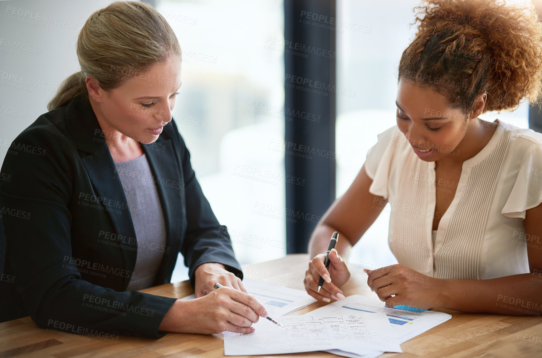 Buy stock photo Shot of two businesswoman sitting in an office discussing paperwork