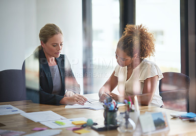Buy stock photo Shot of two businesswoman sitting in an office discussing paperwork