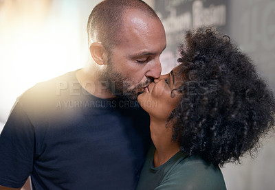 Buy stock photo Shot of a loving couple bonding at home and sharing a tender kiss