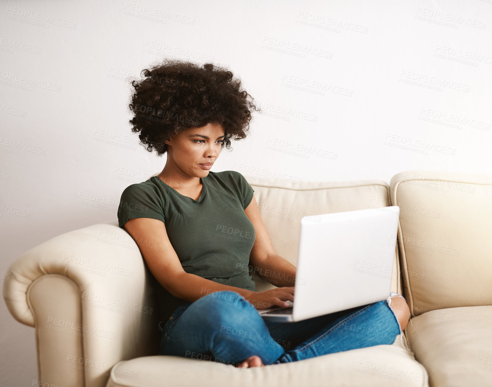 Buy stock photo Cropped shot of a woman using her laptop on the sofa at home with her legs crossed