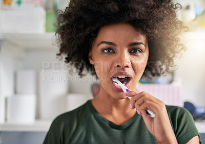 Buy stock photo Shot of a young woman brushing her teeth in her bathroom