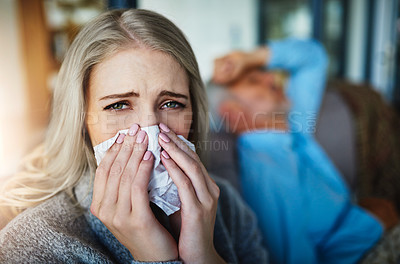 Buy stock photo Portrait of a woman blowing her nose with her husband in the background