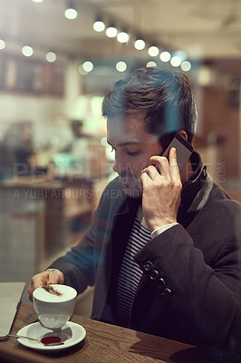 Buy stock photo Cropped shot of a handsome young man using his cellphone while sitting in a cafe