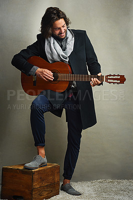 Buy stock photo Shot of a stylishly dressed man posing with a guitar in the studio