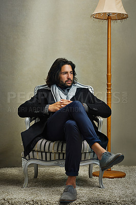 Buy stock photo Shot of a stylishly dressed man sitting on a chair in the studio