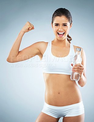 Buy stock photo Studio portrait of an attractive young woman cheering while holding a water bottle against a grey background