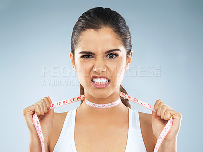 Buy stock photo Studio portrait of an attractive young woman with a measuring tape wrapped around her neck against a grey background
