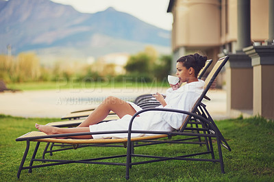 Buy stock photo Woman, relax and tea in hotel outdoor in bathrobe for travel holiday at hospitality resort, morning or calm. Female person, drinking and tanning chair on grass at Bali spa, luxury or stress relief