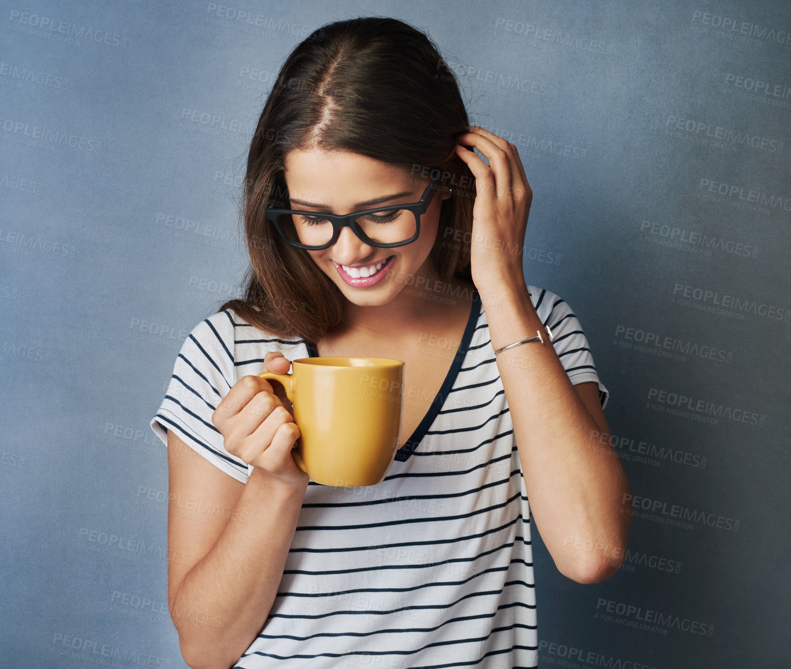 Buy stock photo Woman, student and coffee in studio, drink and shy with glasses on blue background. Hot chocolate, caffeine or energy or health for learner person, hands and matcha latte or green tea and relax