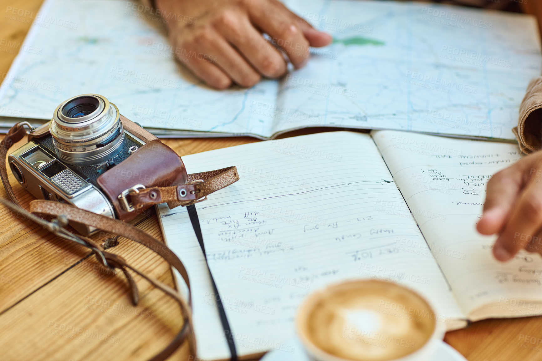 Buy stock photo Shot of an unidentifiable tourist looking at maps and travel journals while enjoying coffee at a cafe