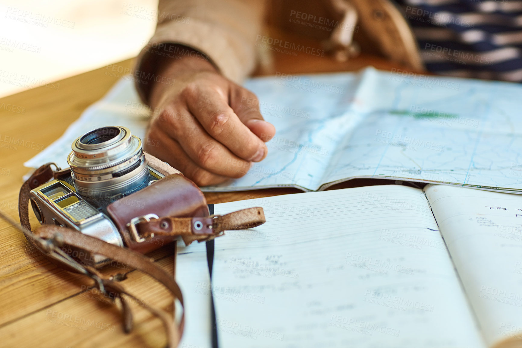 Buy stock photo Shot of an unidentifiable tourist looking at maps and travel journals while sitting a a small table
