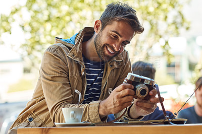 Buy stock photo Shot of a happy tourist taking a picture with his camera while relaxing at a sidewalk cafe