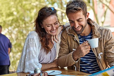 Buy stock photo Shot of a happy tourist couple planning their day while having coffee at a sidewalk cafe
