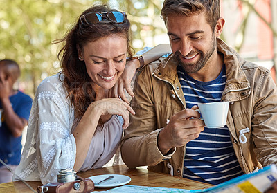 Buy stock photo Shot of a happy tourist couple planning their day while having coffee at a sidewalk cafe