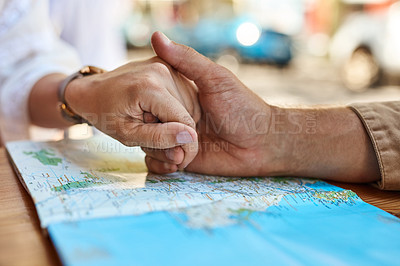 Buy stock photo Shot of an unidentifiable tourist couple holding hands while looking at a map at a sidewalk cafe