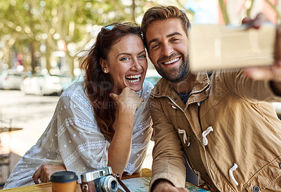 Buy stock photo Shot of a happy tourist couple taking a selfie while relaxing at a sidewalk cafe together