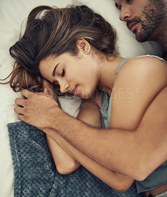 Buy stock photo High angle shot of an affectionate young couple sleeping in their bed