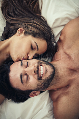 Buy stock photo High angle shot of an affectionate young couple being intimate in bed