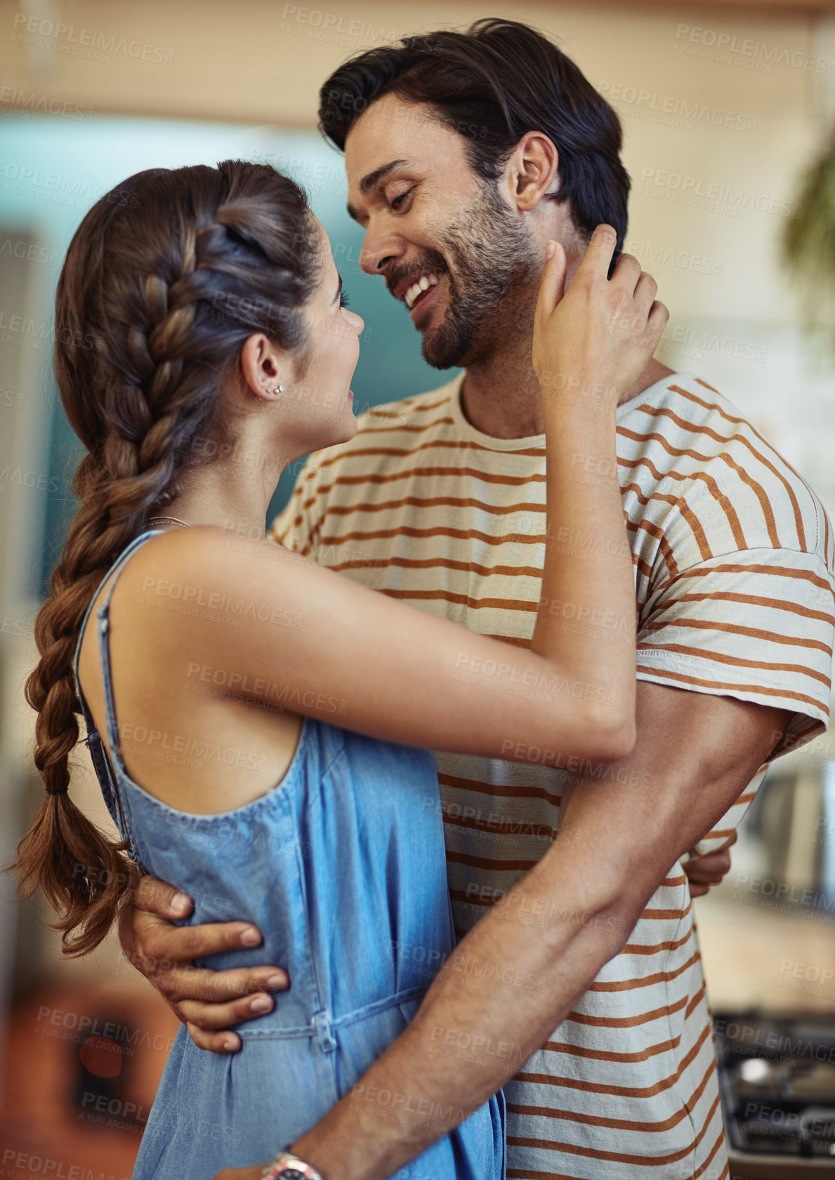 Buy stock photo Shot of an affectionate young couple embracing in their kitchen at home