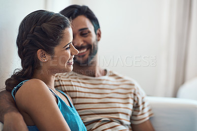 Buy stock photo Shot of an affectionate young couple bonding on their couch at home