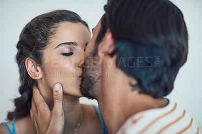 Buy stock photo Shot of an affectionate young couple sharing a kiss on their couch at home