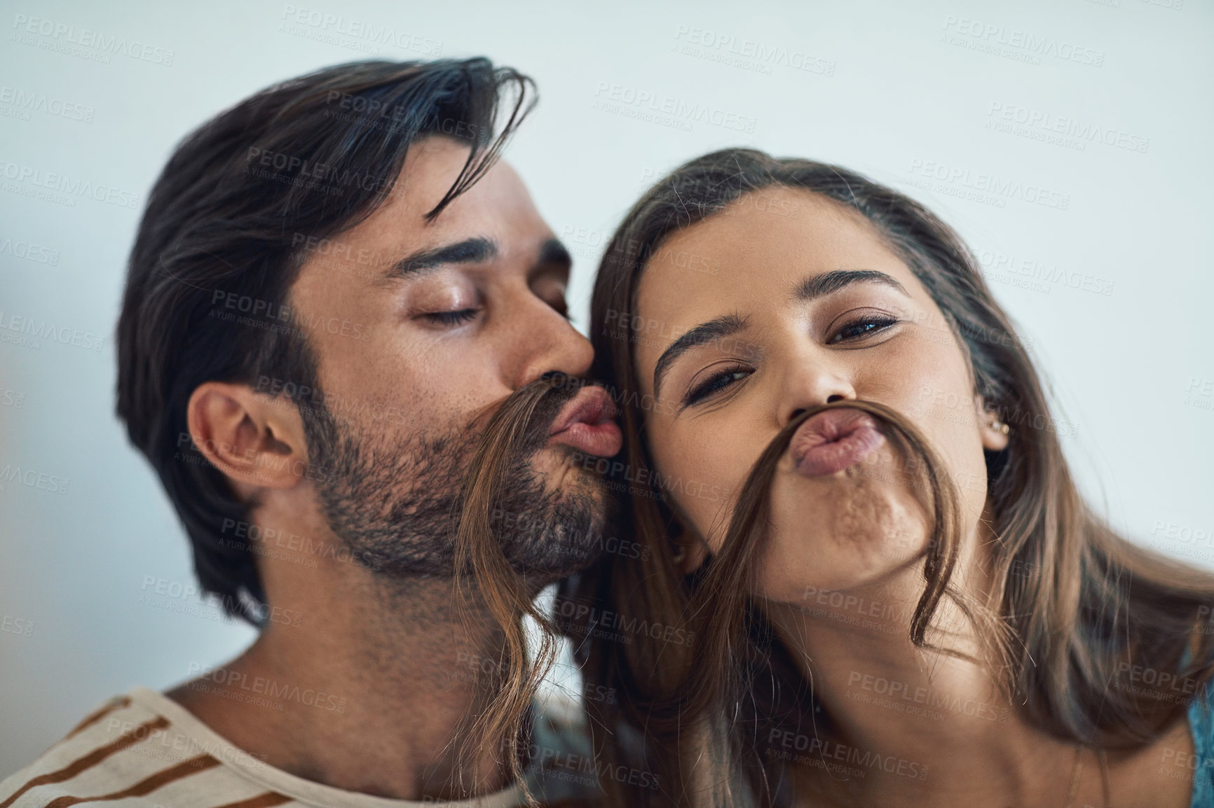 Buy stock photo Couple, home and hair mustache with playful, fun and kissing face with meme, bonding and love together. Young man, woman and silly romance for relaxing pout with care, happiness and comic joke