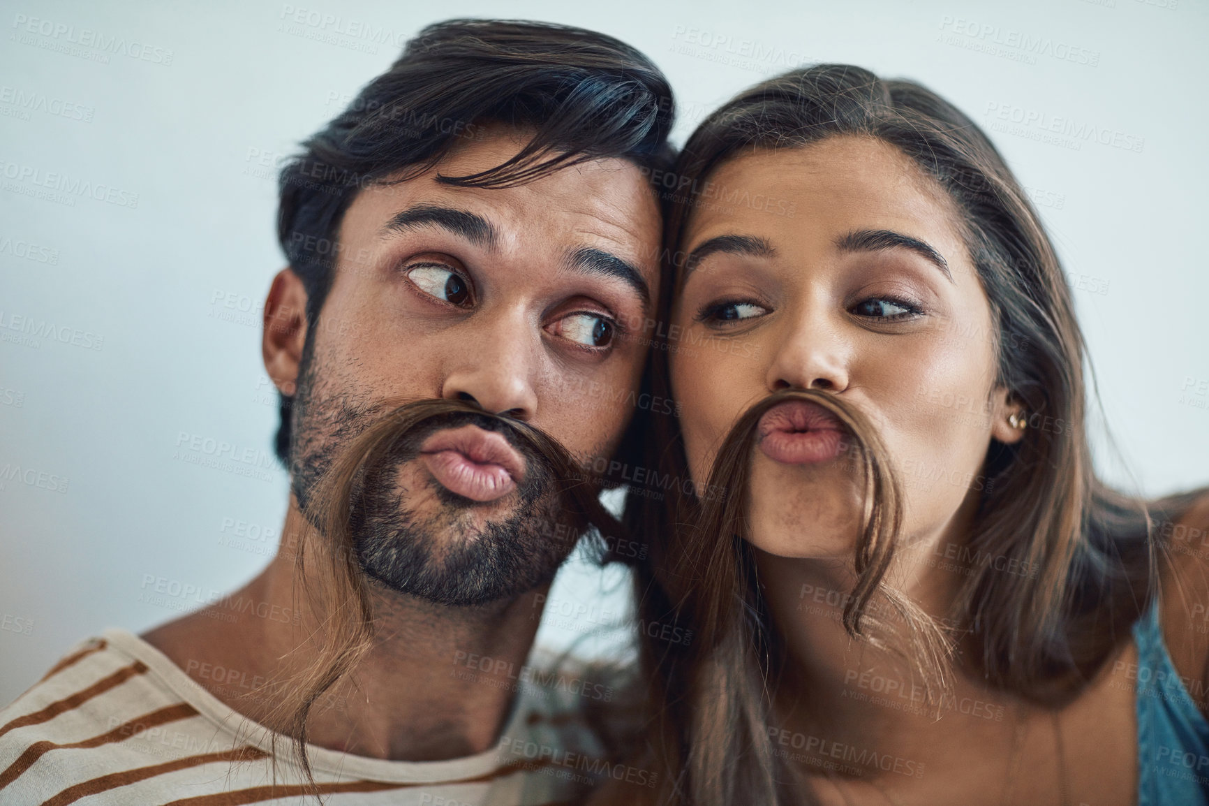 Buy stock photo Couple, home and hair mustache with pout, fun and kissing face with meme, bonding and love together. Young man, woman and silly romance for relaxing smile with care, happiness and comic joke