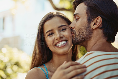 Buy stock photo Portrait of an affectionate young couple sharing a kiss outside