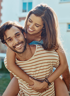 Buy stock photo Portrait of a happy young man giving his girlfriend a piggyback ride outside