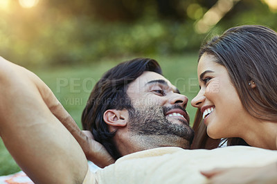 Buy stock photo Shot of an affectionate young couple lying outside on the lawn together
