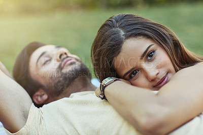 Buy stock photo Portrait of an affectionate young couple lying outside on the lawn together