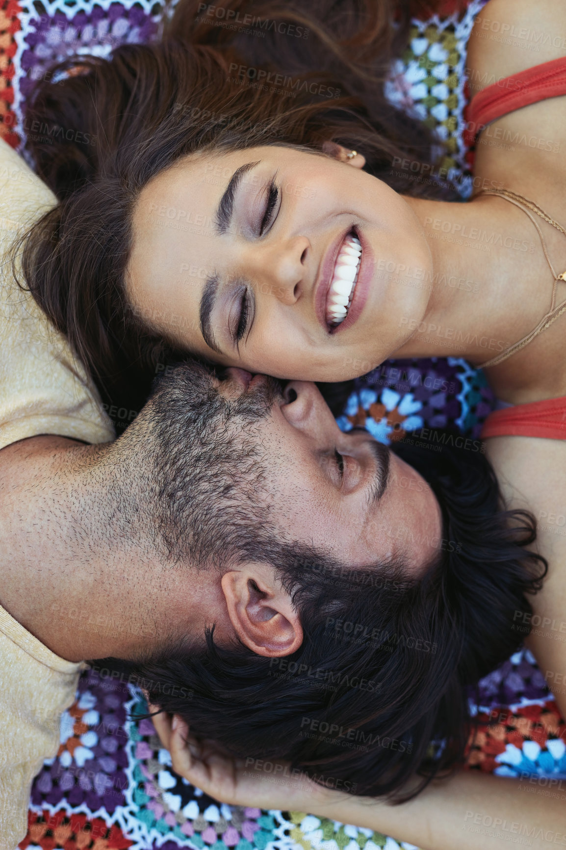 Buy stock photo Couple, kiss and happy on blanket, above or relax on ground for picnic, holiday and bonding. Indian people, man and woman with kindness for connection, smile or care on sheet for vacation in Mumbai