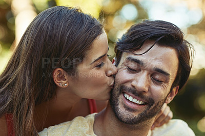 Buy stock photo Shot of an affectionate young couple sharing a kiss outside