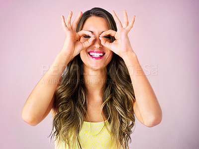 Buy stock photo Studio shot of a beautiful young woman looking through her fingers