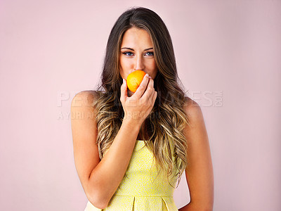 Buy stock photo Studio shot of a young woman eating a orange against a pink background