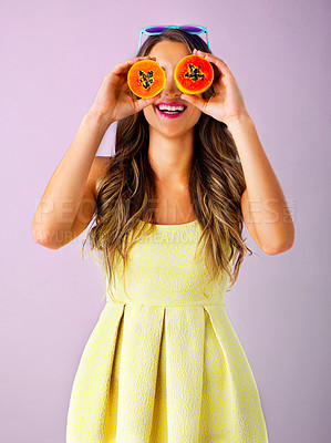 Buy stock photo Studio shot of a young woman covering her eyes with two halves of a paw paw