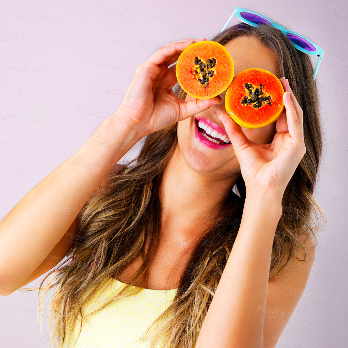 Buy stock photo Happy, papaya on eyes and woman on pink background for healthy eating, nutrition and detox for wellness. Food, smile and person with fruit for organic diet, wellbeing and natural vitamins in studio