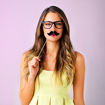 Buy stock photo Studio shot of a young woman holding a mustache prop to her face against a pink background