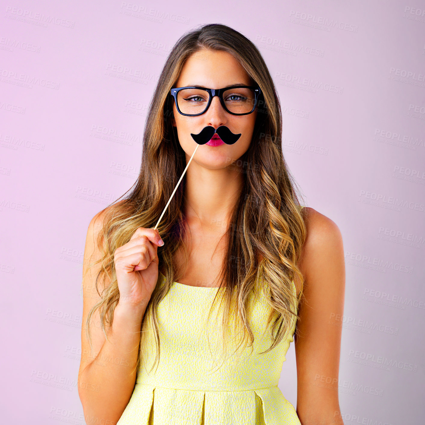 Buy stock photo Studio shot of a young woman holding a mustache prop to her face against a pink background